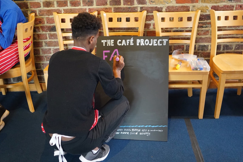 Picture of Cafe Project participant writing up the menu board for the day